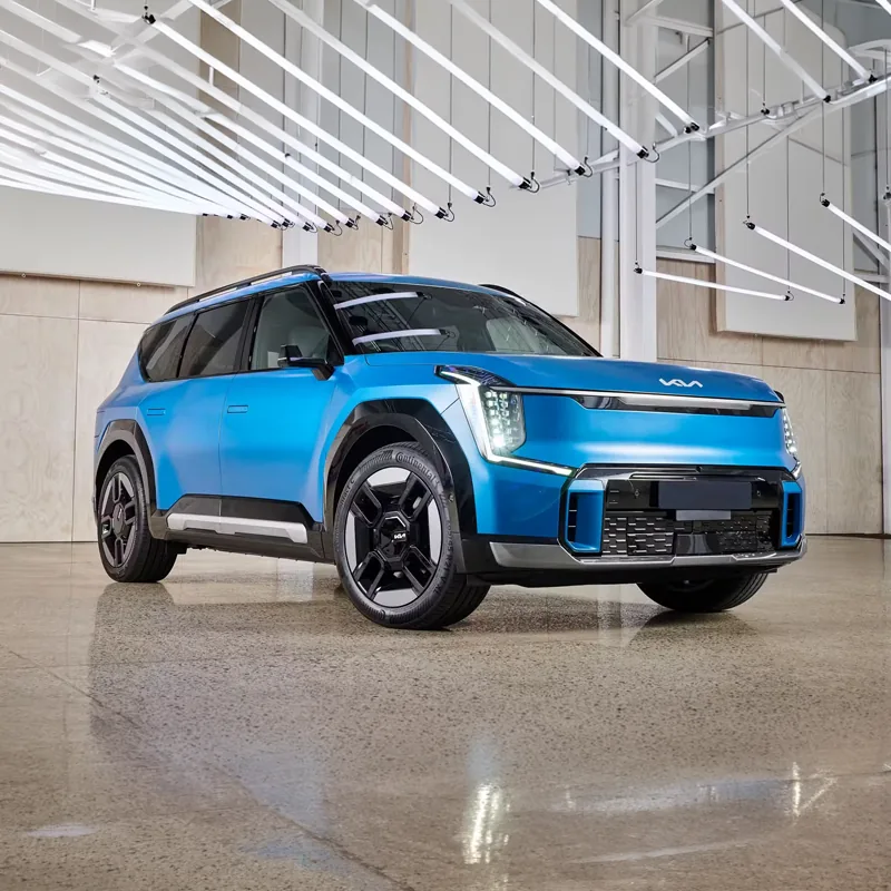 Blue Kia EV9 electric SUV displayed indoors under modern linear ceiling lights.